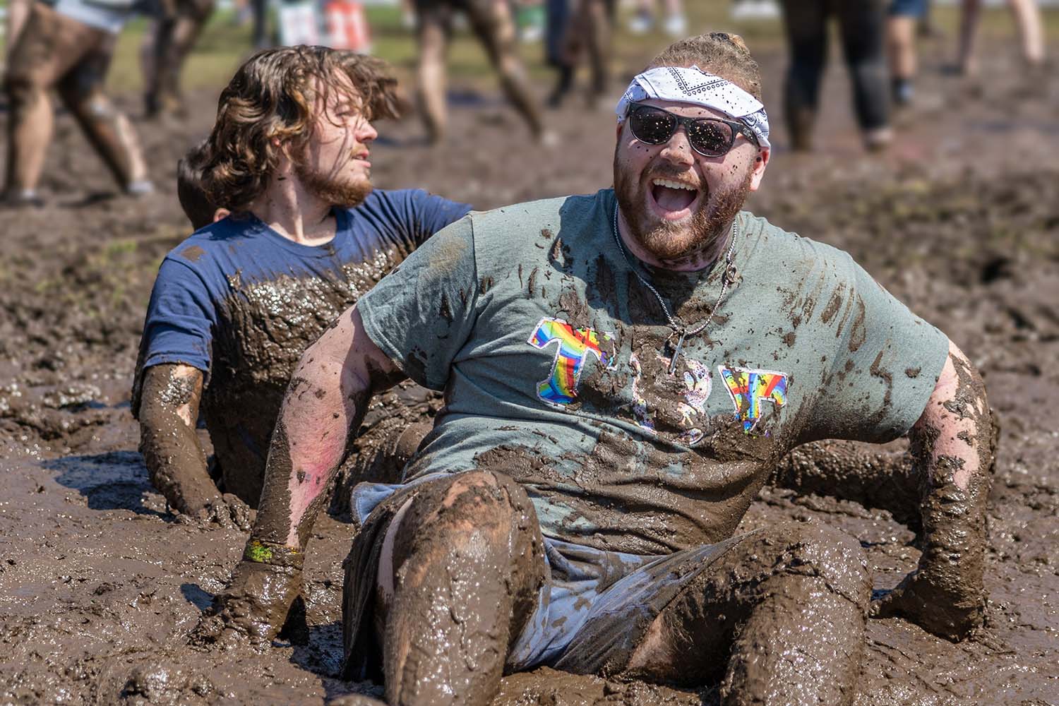 students laugh as they fall into the mud